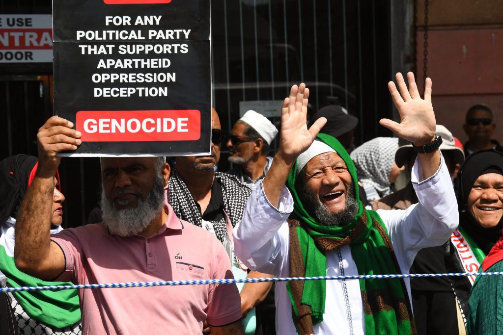 Protesters hold placards and Palestinian flags as they march through Cape Town.