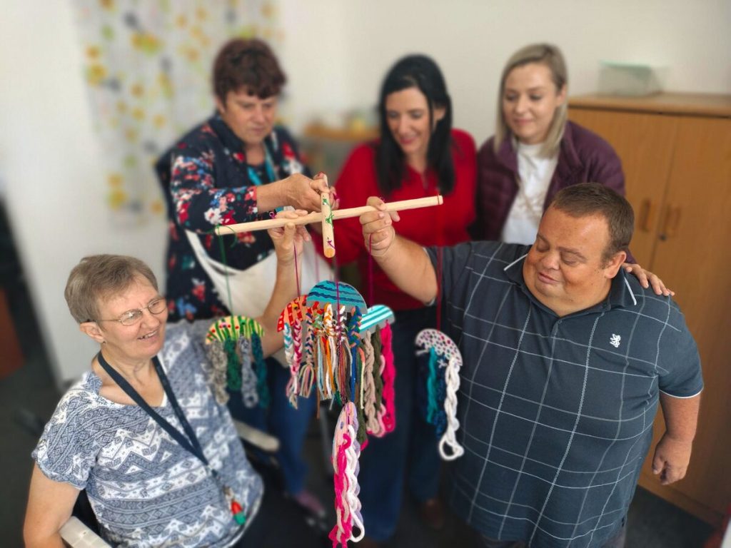 By een van die handgemaakte artikels is, voor, Ronel van den Heever en Enrico du Toit (albei van Vrystaat-Nasorgsentrum); agter hulle is nog 'n inwoner, Lizzie Kruger (links), saam met Elmarie Prinsloo (uitvoerende hoof van Bloemskou) en Alicia van Heerden (organiseerder van Bloemskou se kreatiewe handwerk en kuns).  FOTO: Lientjie Mentz