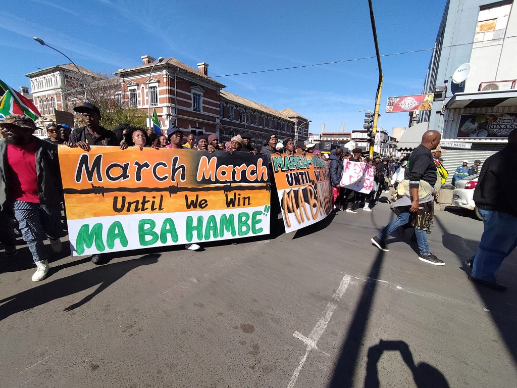 Die March and March-optog draai in Charlotte Maxekestraat in. Die banier lees Mars, Mars totdat ons wen. Hulle met loop.