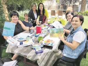 Vroue nooi ander om saam in tuin te skilder, ontspan