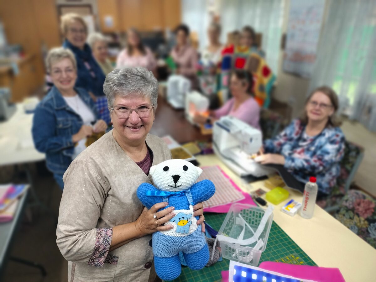 Iessie Steenberg (voor) met 'n beertjie by van die flukse vroue wat bydra om handgemaakte produkte vir verskillende instansies in die stad te maak. By haar is van links René Barnard, Jenny Sheldon, Gerda Cronjé, Colleen Voetz, Gerda Breytenbach, Susan Fresham, Sannie Viljoen, Heléne von Maltitz en Mara Swanepoel.