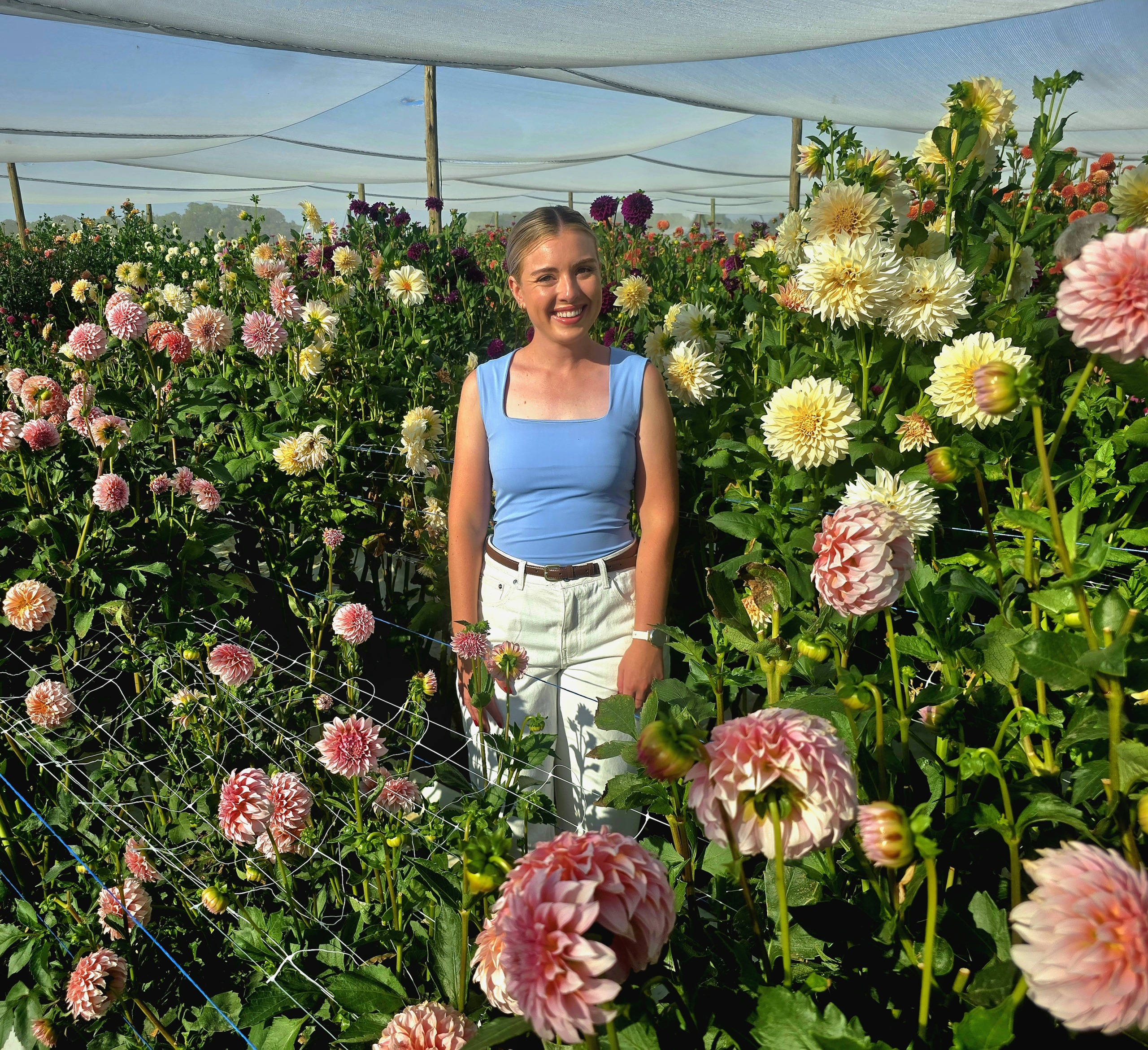 Jong boervrou deel liefde vir blomme wyd en oorvloedig, soos armsvol ruikers