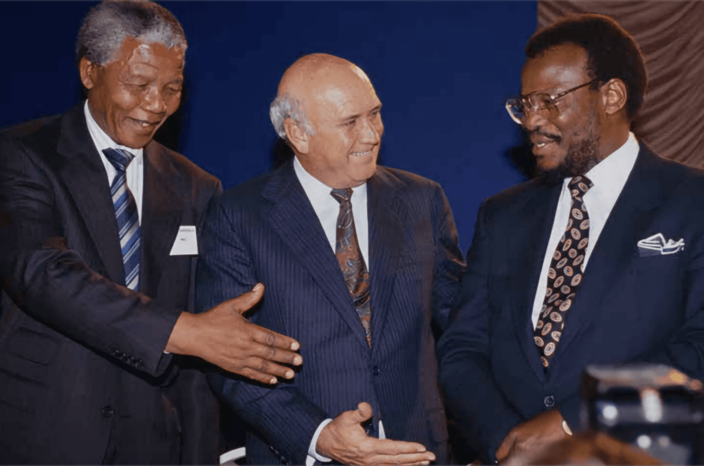 Nelson Mandela (ANC), F.W. de Klerk (Nasionale Party) en Mangosuthu Buthelezi (Inkatha Vryheidsparty) skud hande kort voor die ondertekening van die Vredesooreenkoms.