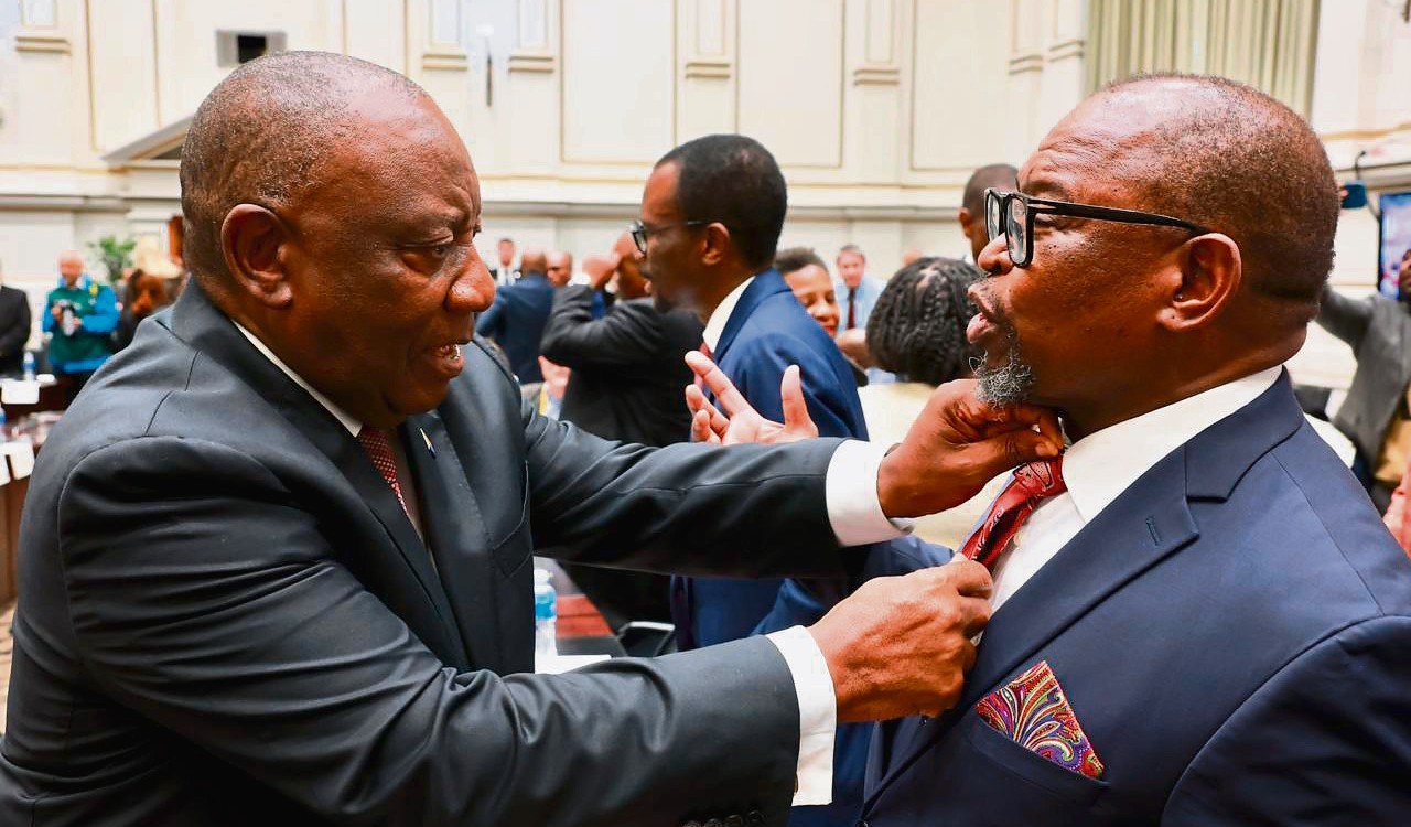 Pres. Cyril Ramaphosa maak die minister van finansies, Enoch Godongwana, se das reg voordat Godongwana sy mediumtermynbegrotingstoespraak lewer. Foto: GCIS.