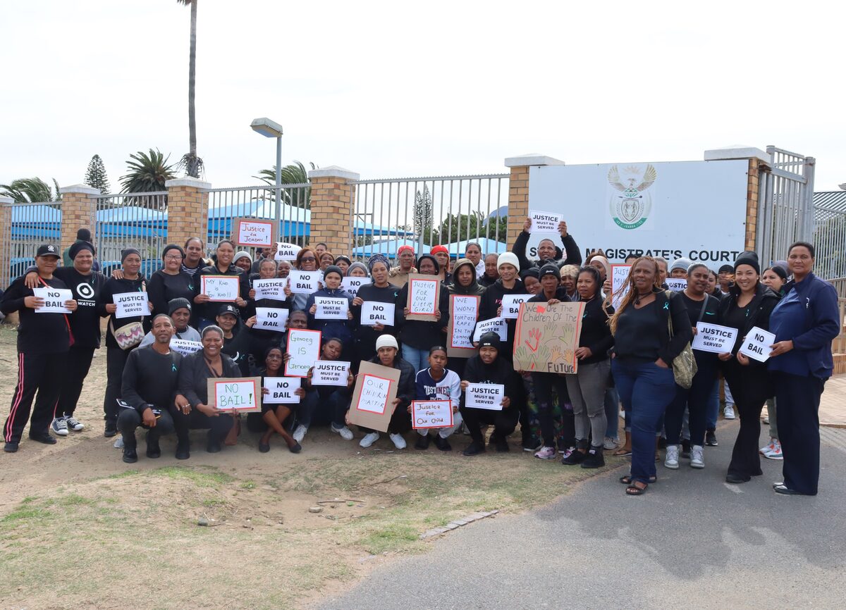 Skare buite Strand-landdroshof op 7 April wat geregtigheid eis vir beweerde negejarige slagoffer.