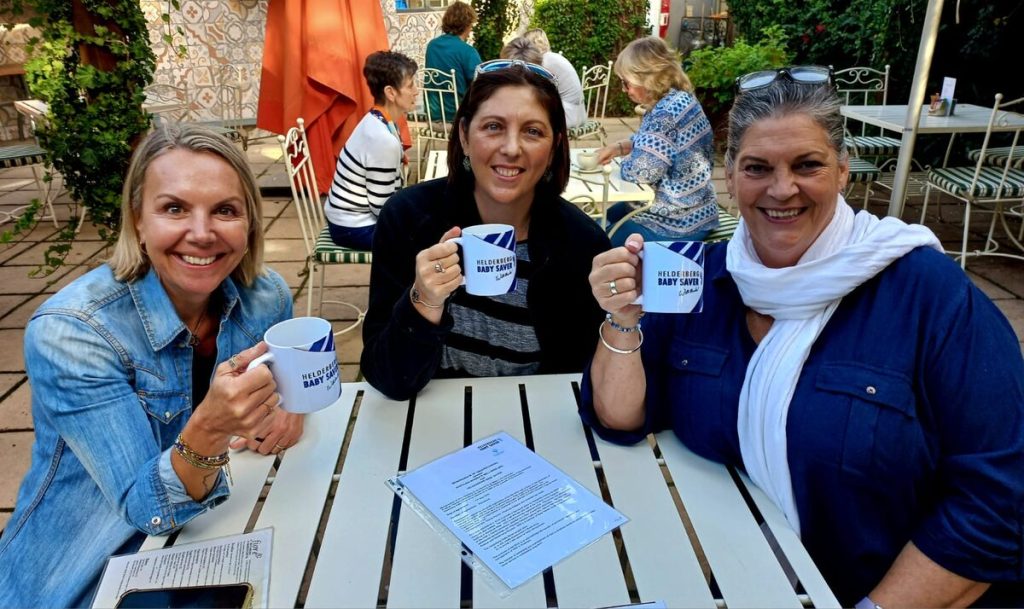 Khethani Women's Wellness trio Frances, Amanda-Lea, and Sophia discuss the Helderberg Baby Saver over coffee.