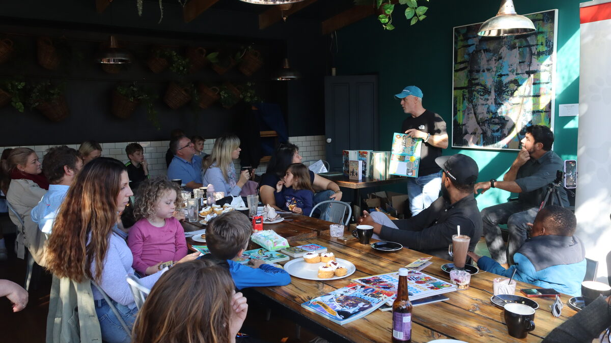 Murray Williams showing an illustration from 'My First African Adventure' to the audience at Millhouse Kitchen.