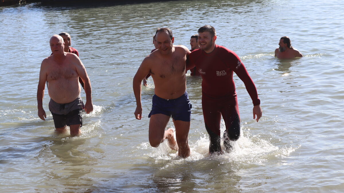 Smiling participants and NSRI Station 9 crew exiting the water after the Winter Solstice Swim in Gordon's Bay.