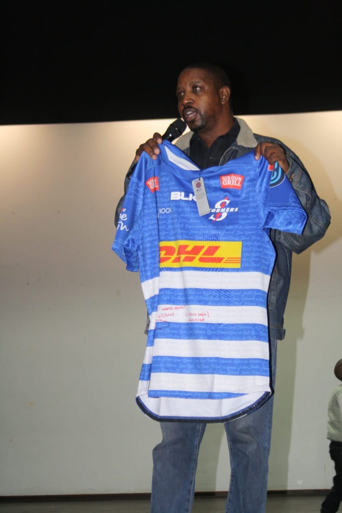 Gilbert Wewers van Rawson Properties vertoon getekende Stormers-rugbytrui voor veiling vir rehabilitasiefondse.