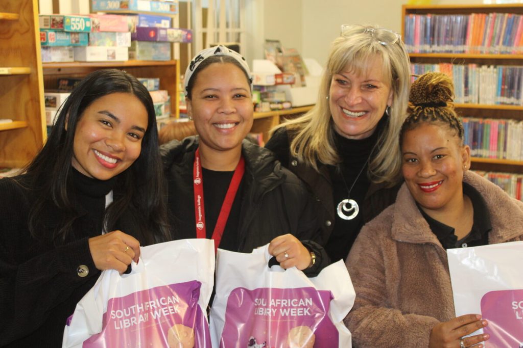 Strand Rotary distributes 150 beanies at Gordon's Bay Library for Mandela Day with ACVV representatives