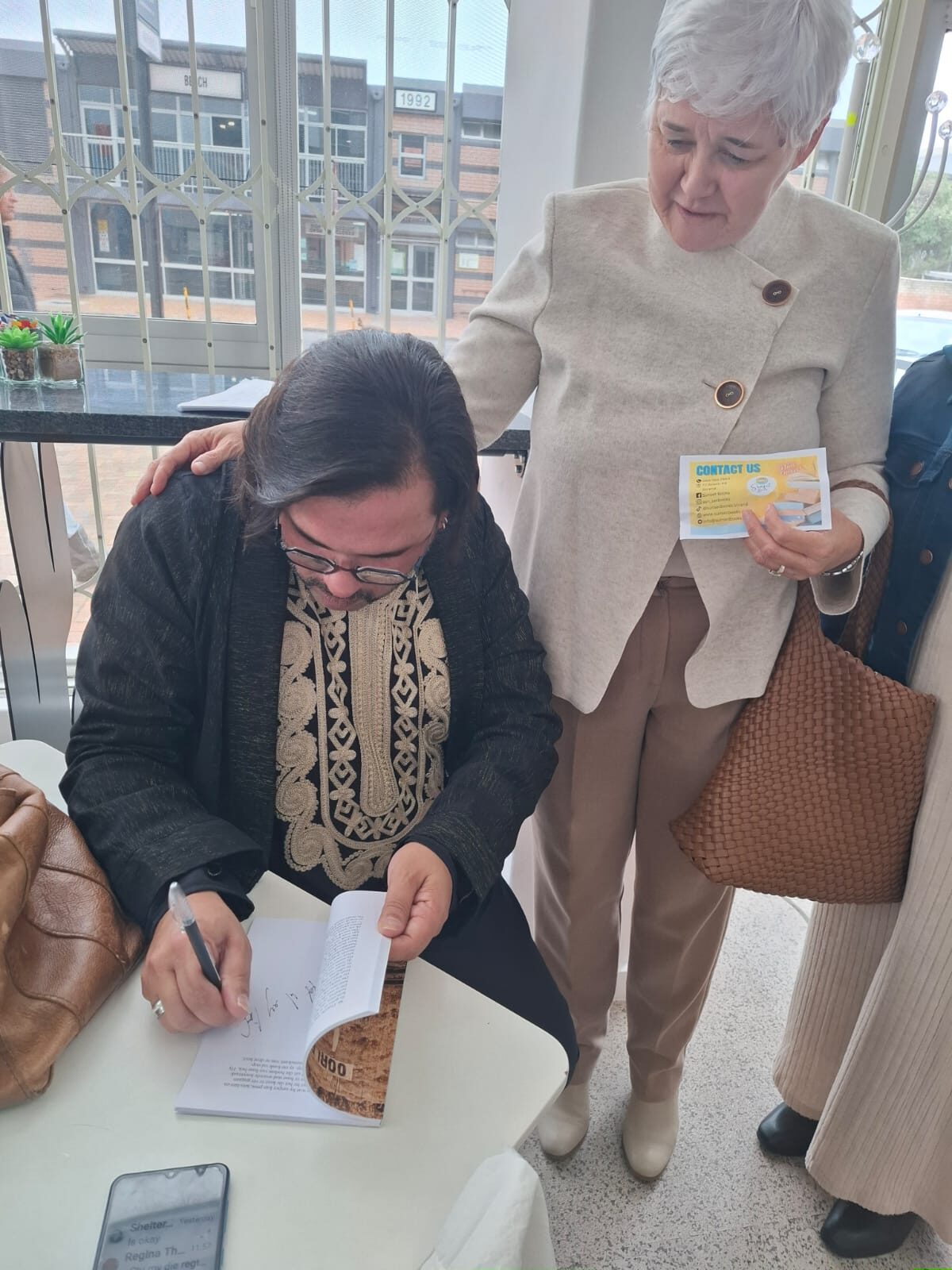 Sannya Smith teken 'n kopie van Oorlewende vir Michelle Turner van ROTO.