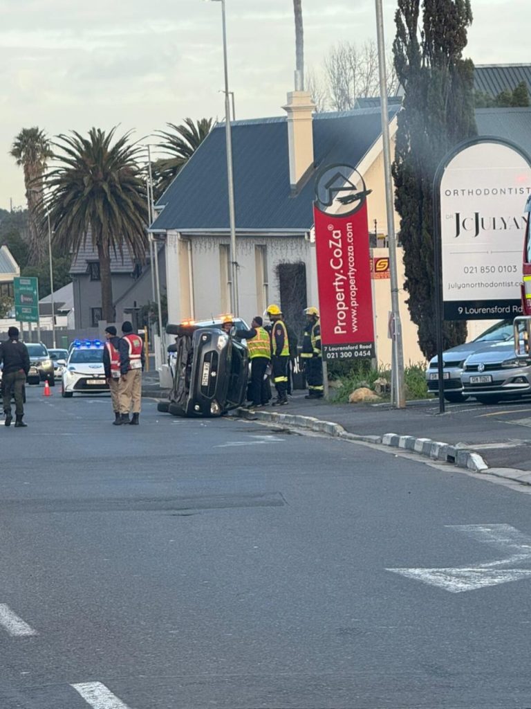 Emergency services attend vehicle collision scene on Lourensford Road where car flipped on its side.