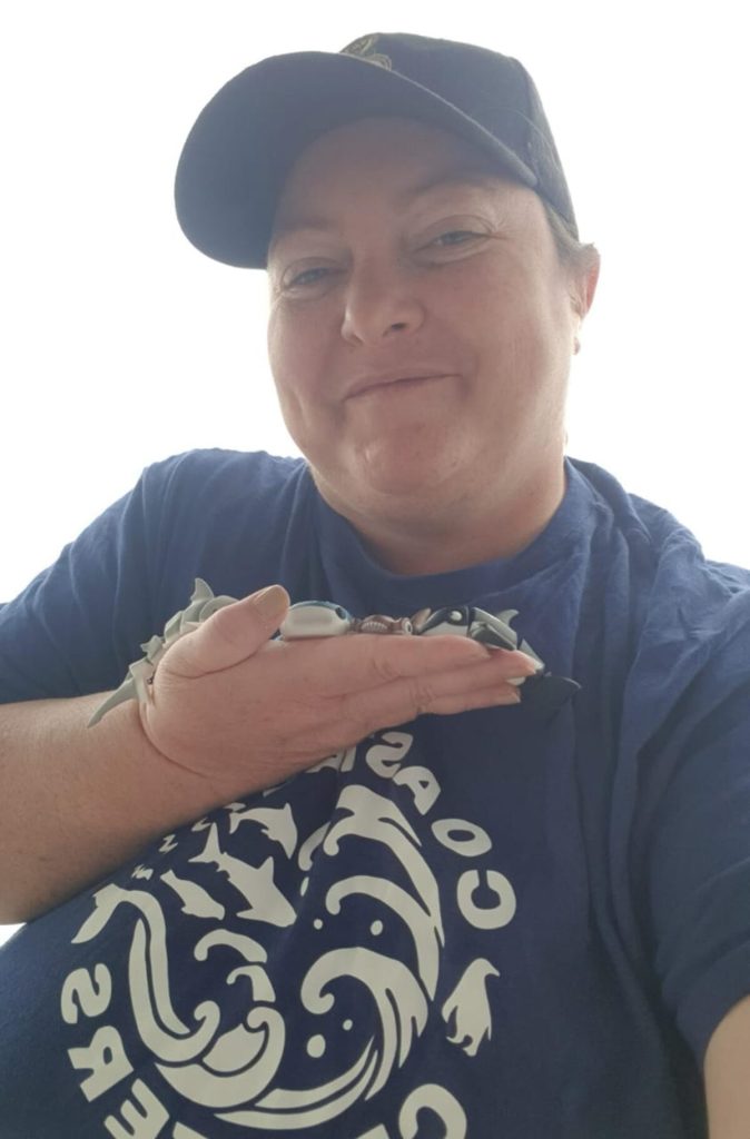 Taryn Flee holding colorful 3D printed marine animal toys from her Coastal Critters fundraising collection.