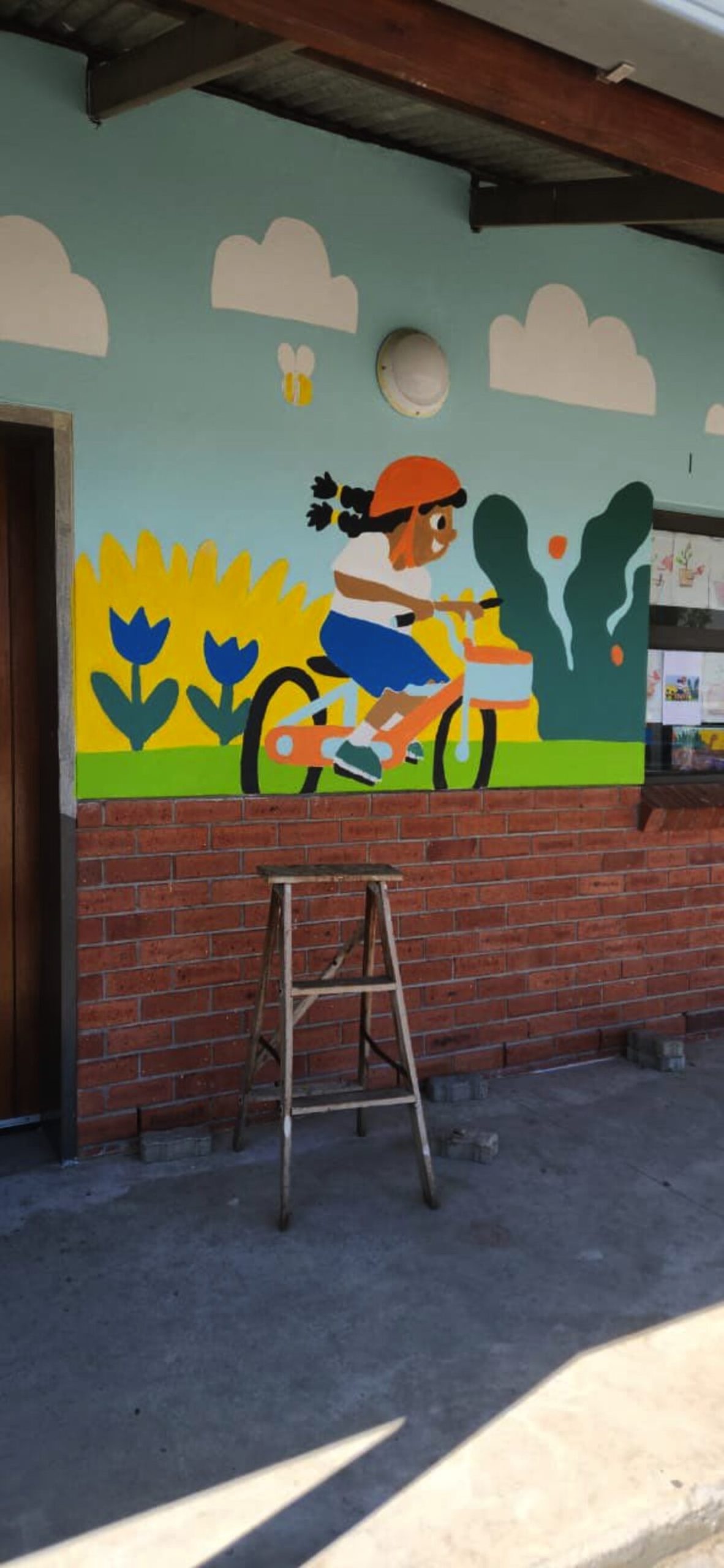 Tekening van meisie wat fiets ry, geverf op Altena se muur