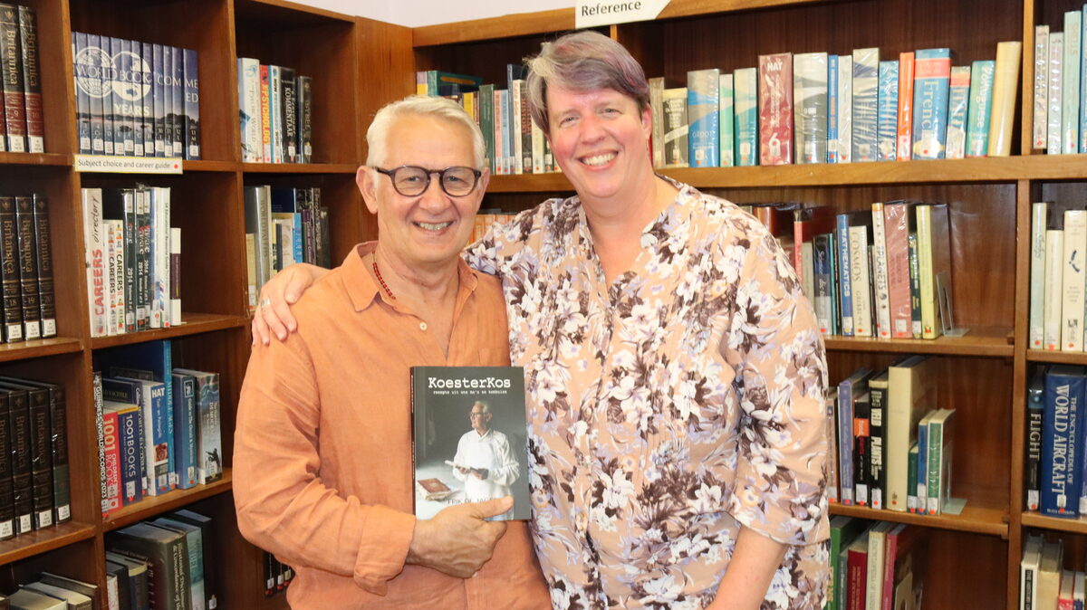 Frik de Jager en gast glimlag terwyl hulle by die bekendstelling kuier.