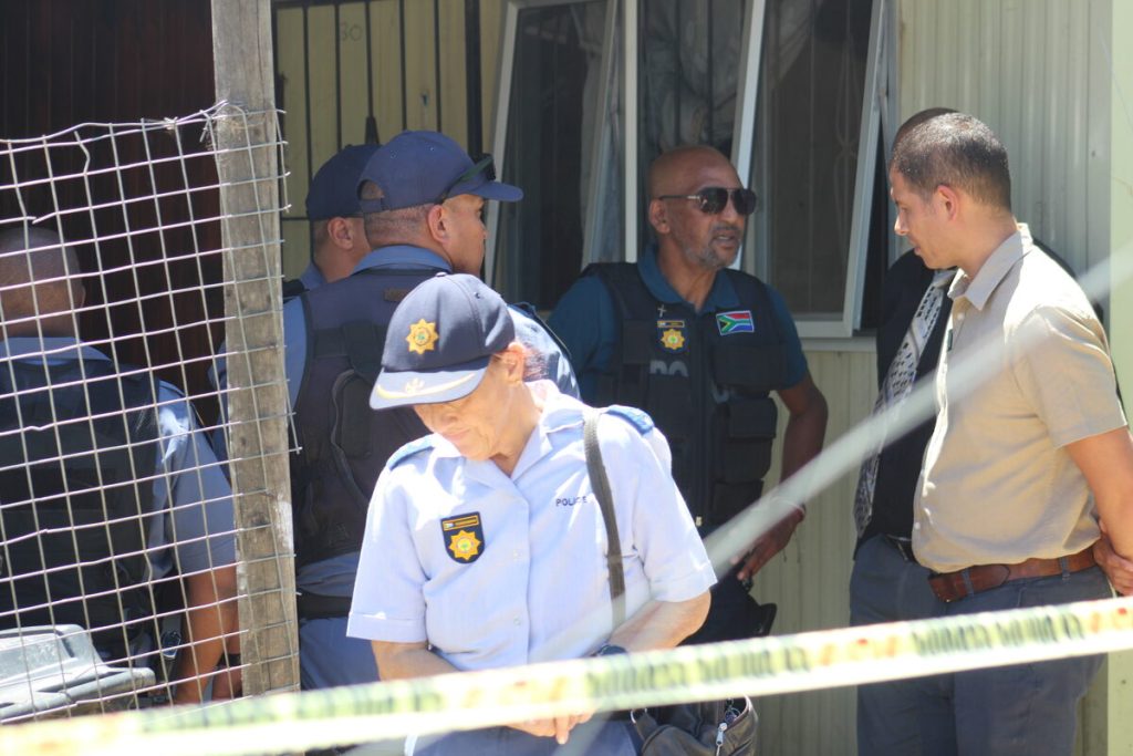 Polisiebeamptes het die ondersoek voortgesit en die misdaadtoneel vir leidrade deursoek. Foto: Jamey Gordon