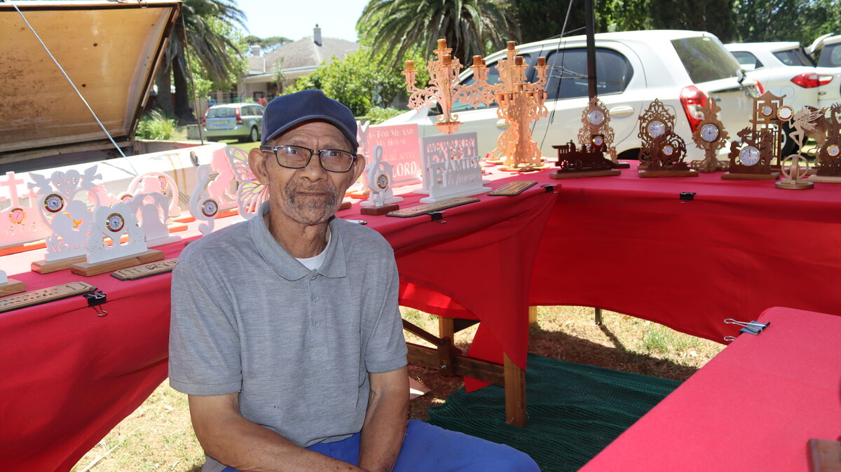 Carpenter Douglas Carelse displays handcrafted timepieces and wooden creations at his market stall.