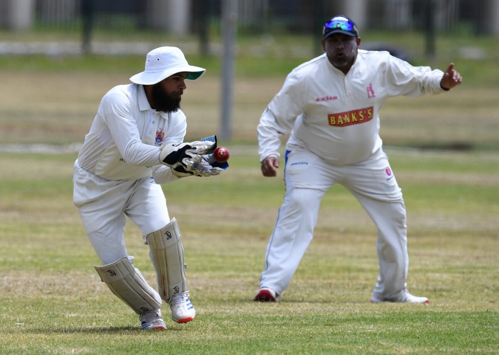 Wicketkeeper for HH Irshaad Salie pouches a ball while slip Marwaan Wanza looks on.