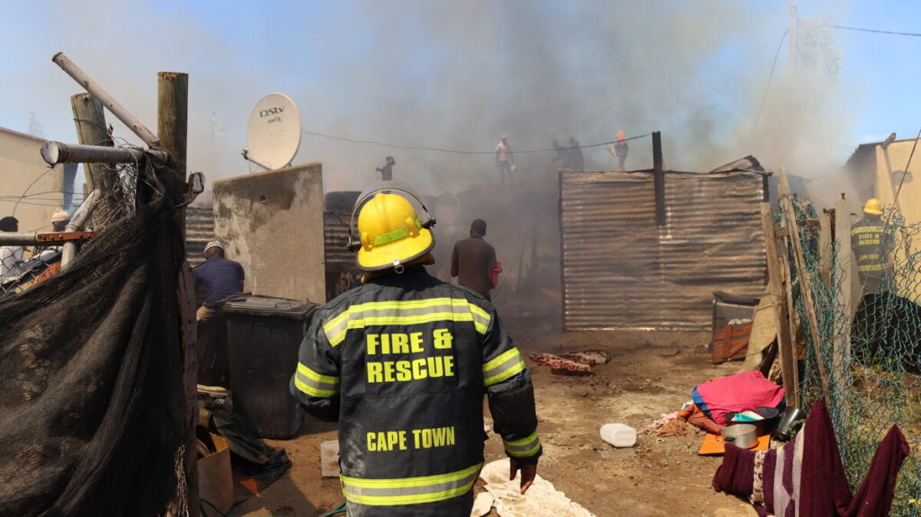 Residents on rooftops with buckets of water fighting fire in Kwezi Street, Lwandle.