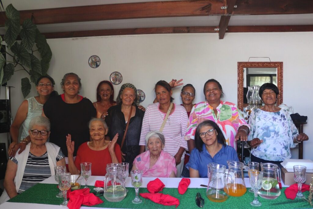 Elderly residents enjoying Christmas lunch and receiving food packages at Lourensia Park event.