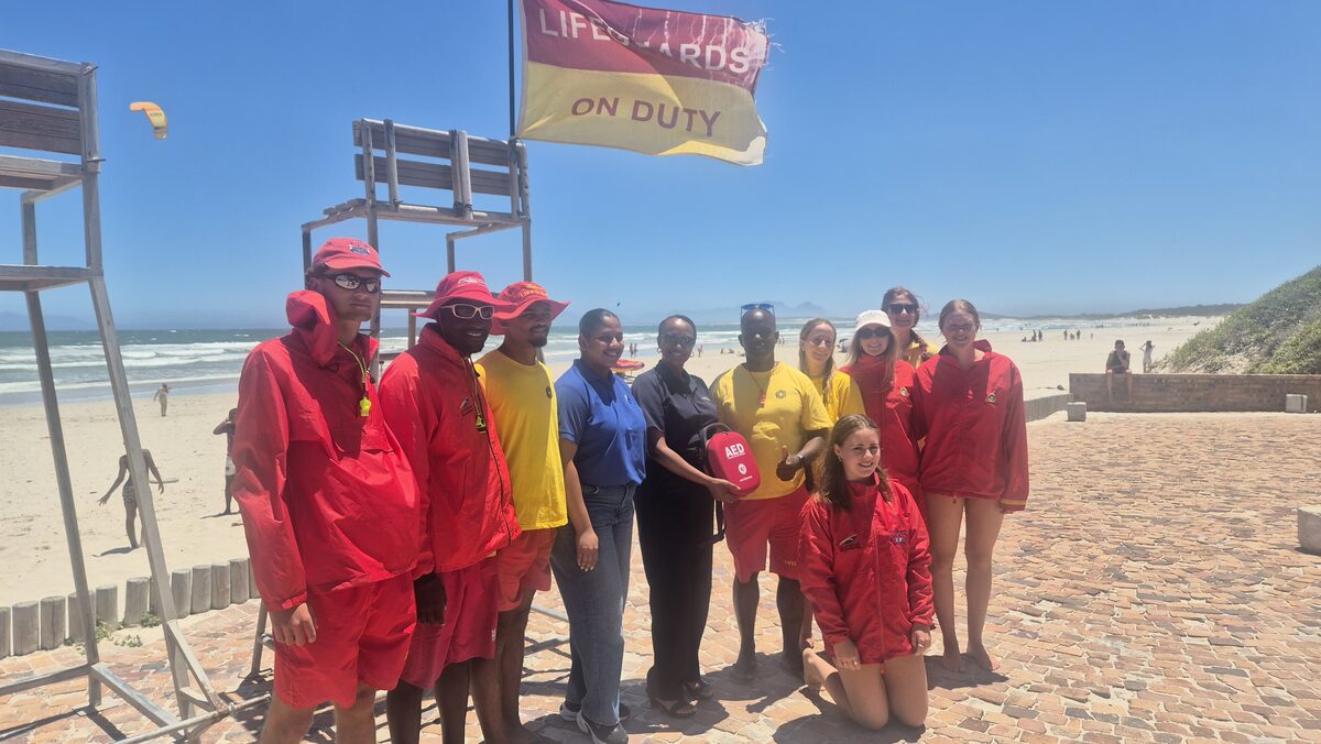 Busamed Paardevlei Hospital representatives presenting AED equipment to Strand Lifesaving Club lifeguards"