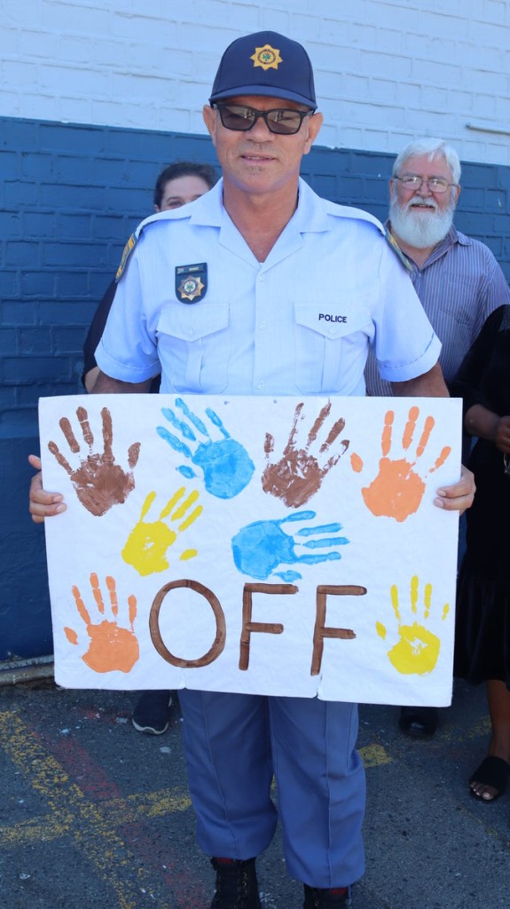 Nico Beukes in uniform wat saam met mense loop in 'n optog teen geweld teen vroue en kinders