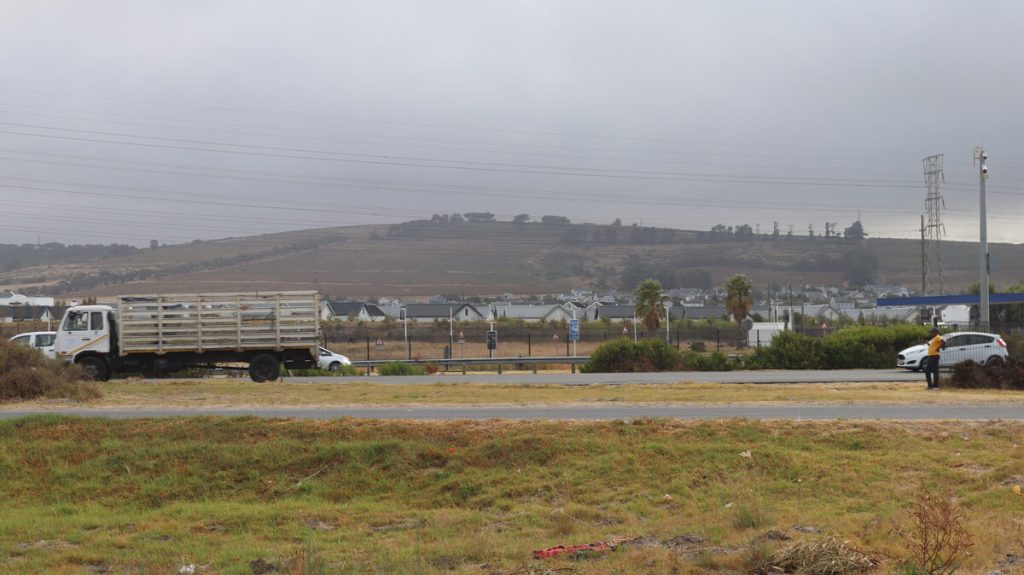 Voetganger langs gebreekte heining by snelpad