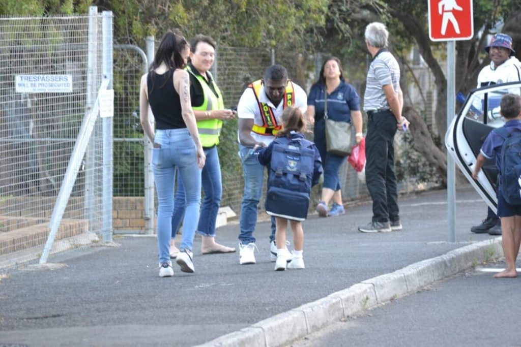 Sgt Naidoo presenting ruler to happy primary school learner