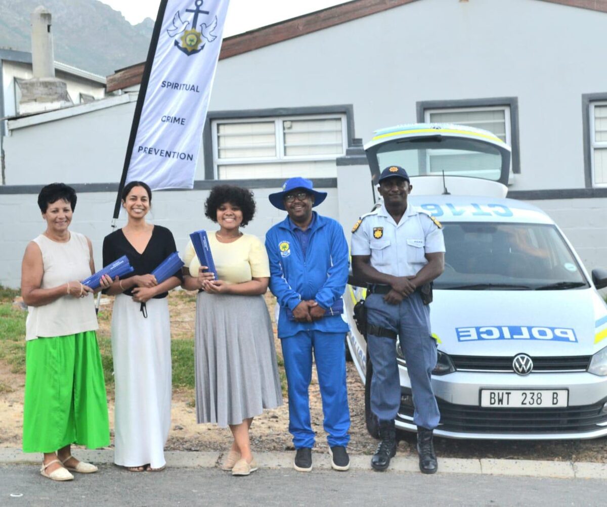 Five community volunteers smile while distributing anti-bullying rulers to learners at Gordon's Bay Primary School