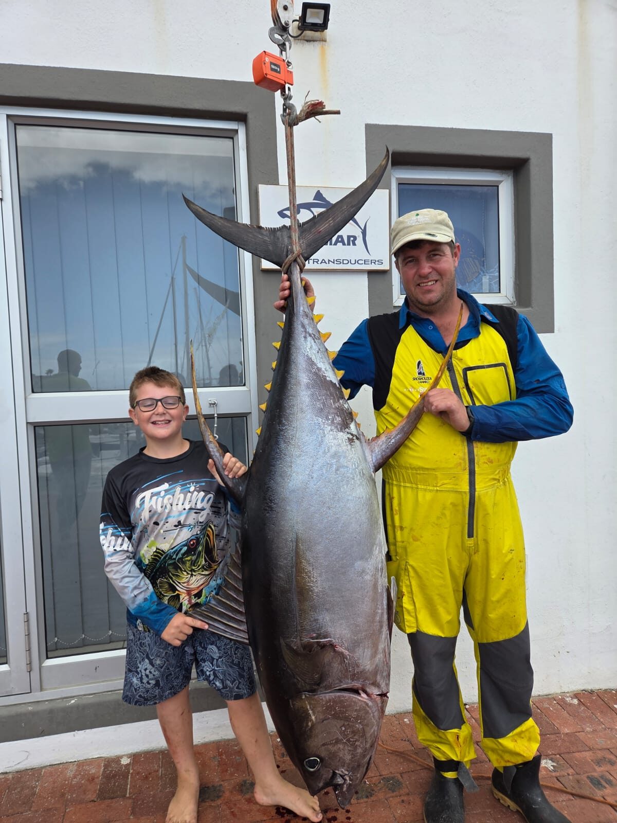Young angler DeWet van der Walt and his father, Dirk, pictured alongside the monster yellowfin tuna catch.