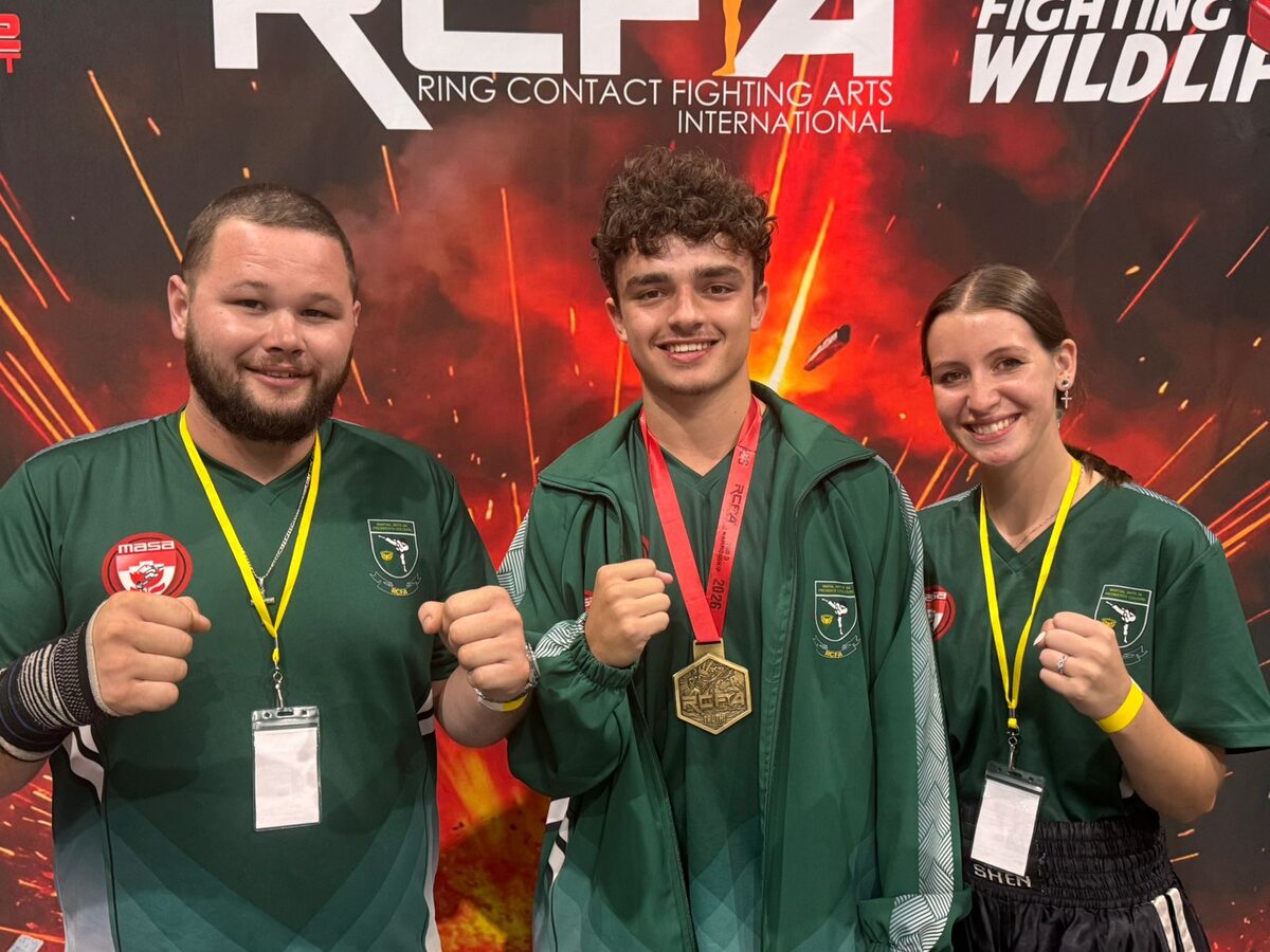 Reuben Venter holds his RCFAI world gold medal alongside mentors Sensei Joshua Conway and Sensei Angi Nunez.