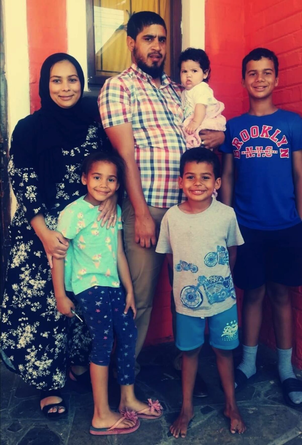 Familieportret met vyf lede - drie volwassenes en tieners agter, twee jonger kinders voor.