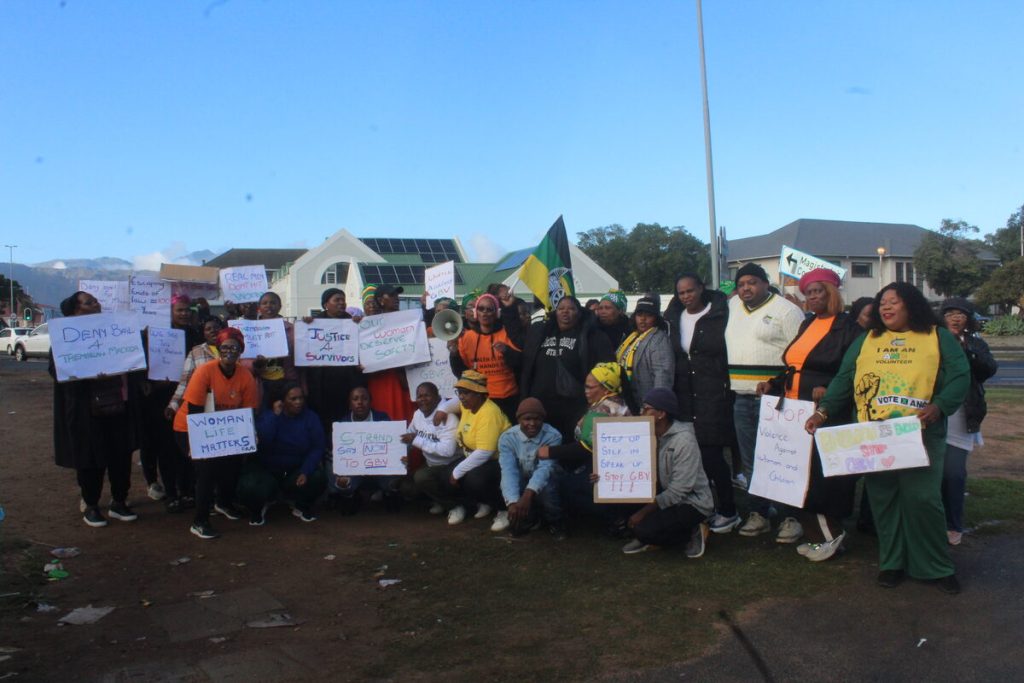 Group of people outside Strand Magistrates' Court showing solidarity with alleged victim during bail hearing.