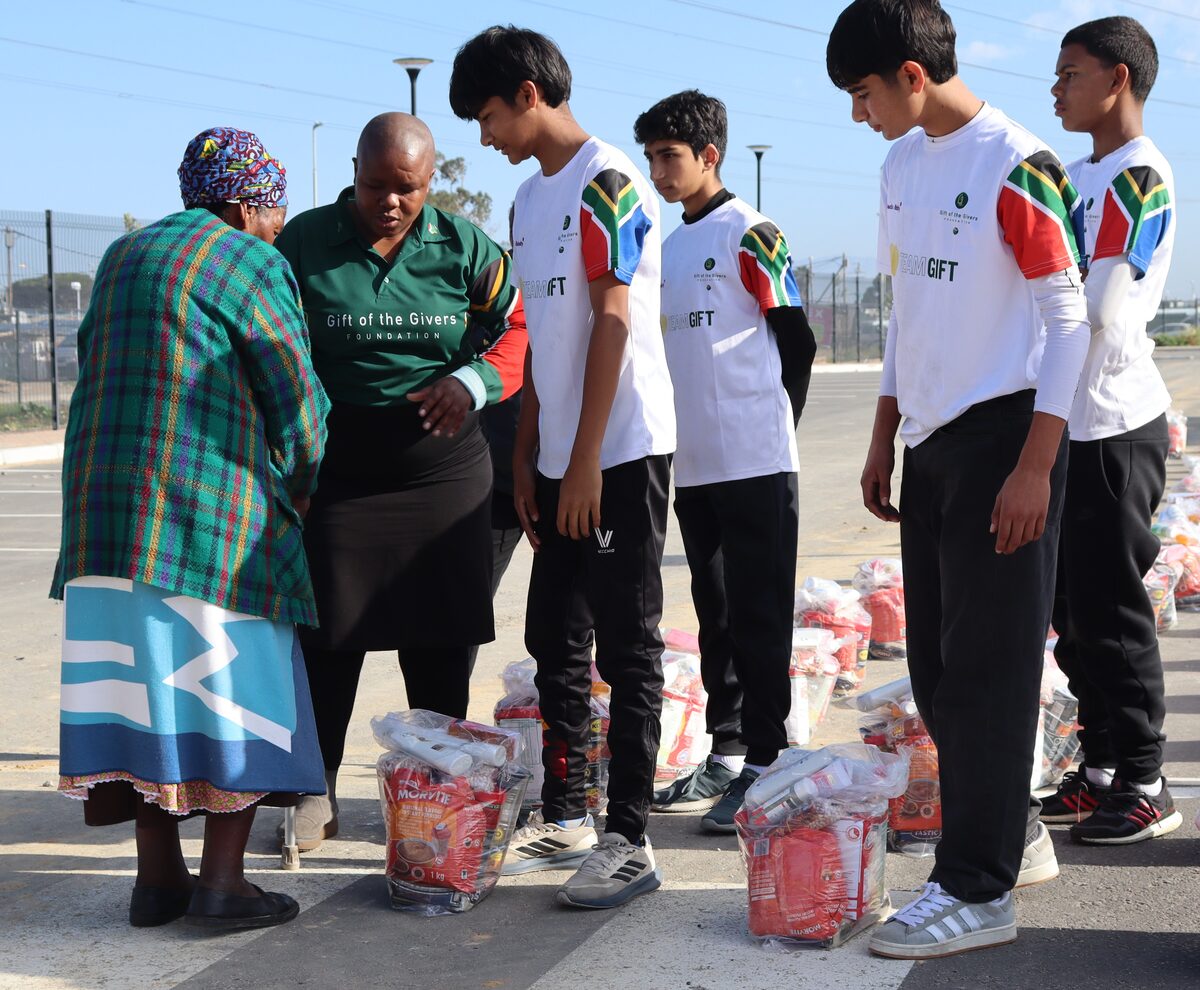 An elderly resident receives a food parcel from Rondebosch Boys' High School learners.