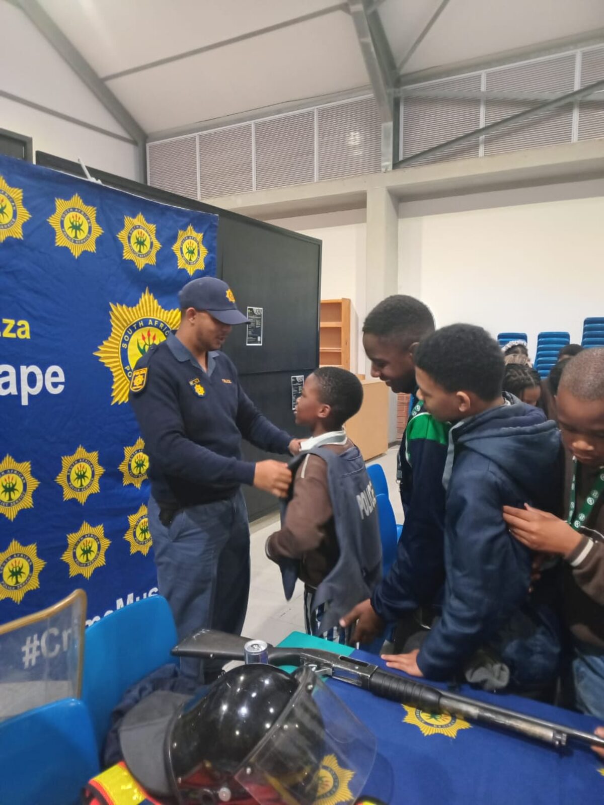 Sgt Ziyaad Julies demonstrates police gear by fitting a learner with a bulletproof vest.