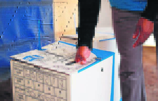 A voter inserts a ballot into a ballot box.
