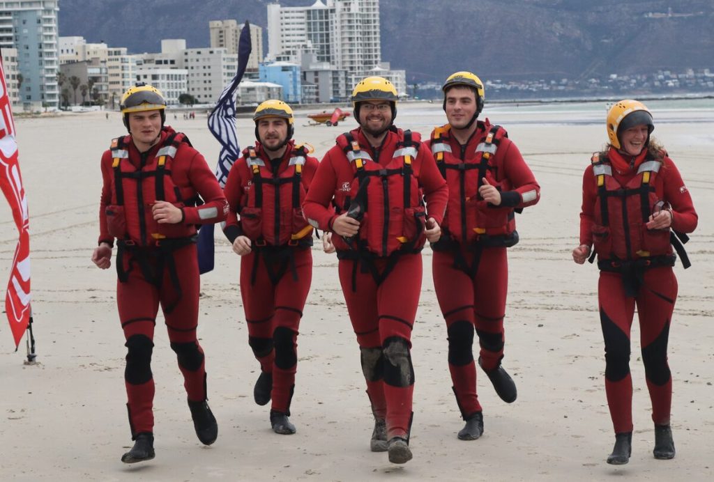 Five NSRI Station 9 crew members cross the finish line together
