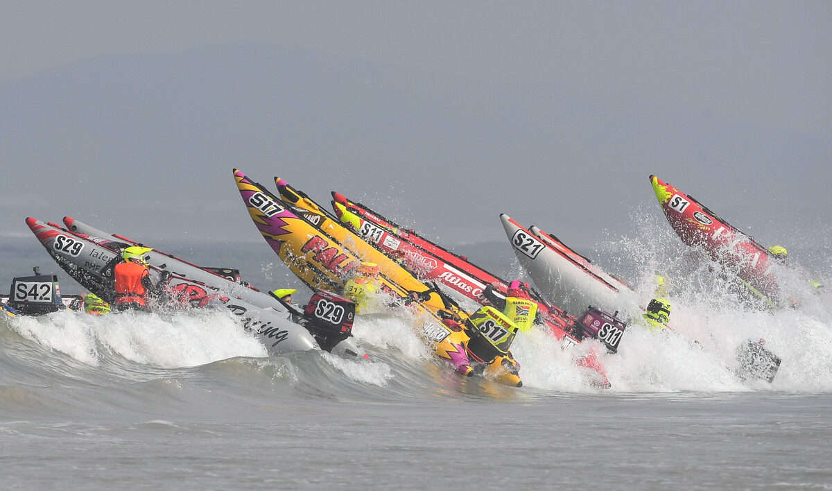 A pack of inflatable powerboats launches from the start line, battling murky, grey sea conditions at Strand Beach. Photos: Peter Bee
