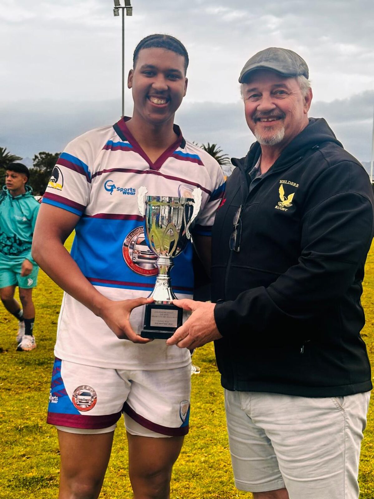 Jaden Pieterse of Macassar RFC accepts the third place trophy from Bokkie Carstens of Helderberg Rugby Club.