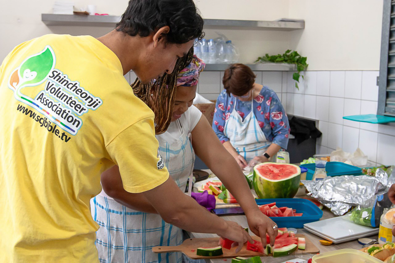 'n Shincheonji-vrywilliger help een van die amptenare van die Stellenbosch-munisipaliteit in die kombuis.