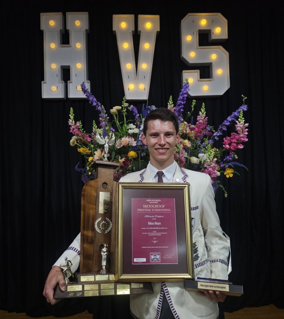 Willie Odendaal staan met verskeie trofees en 'n sertifikaat.