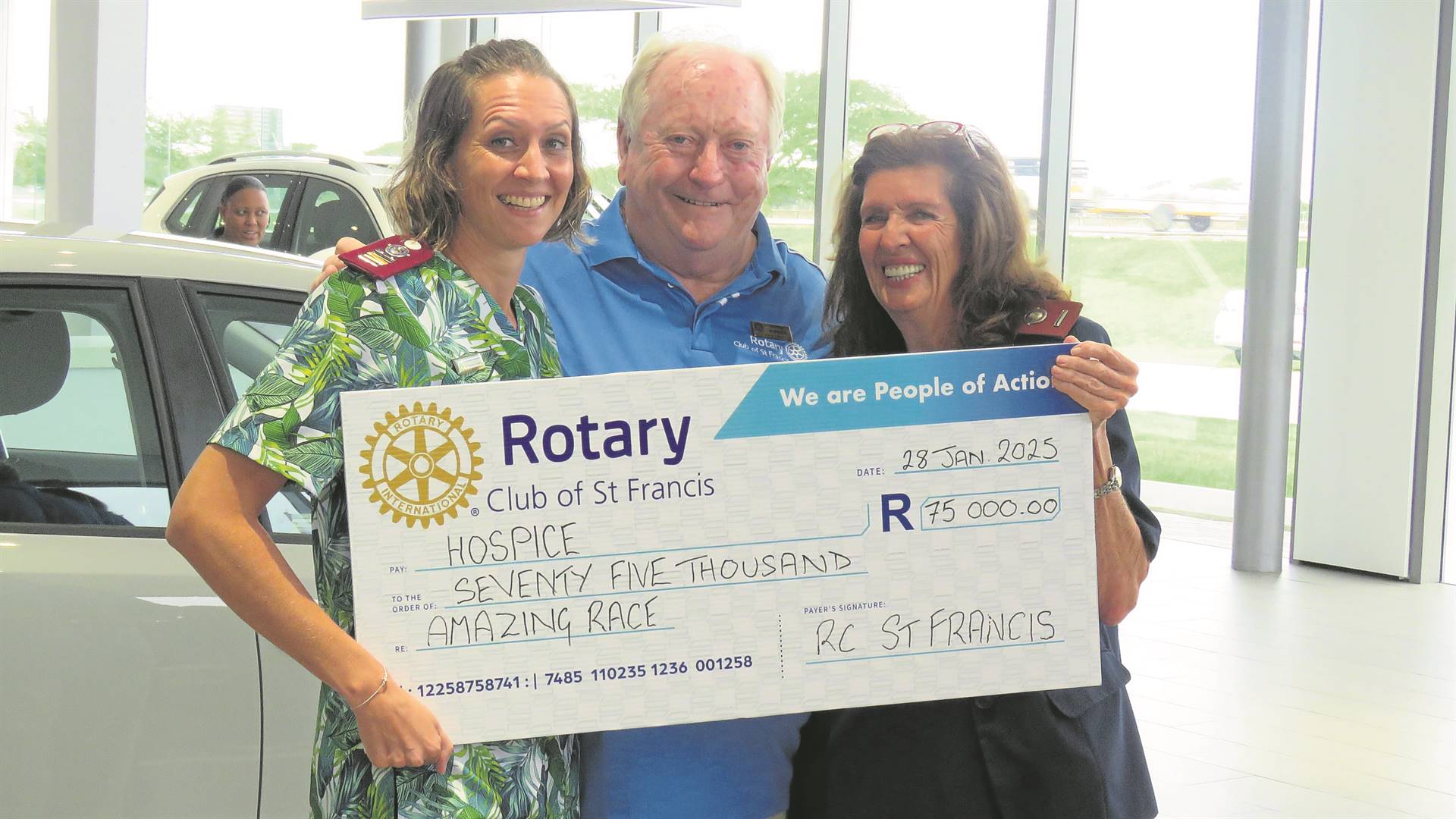 Three people standing alongside each other holding a large cheque.