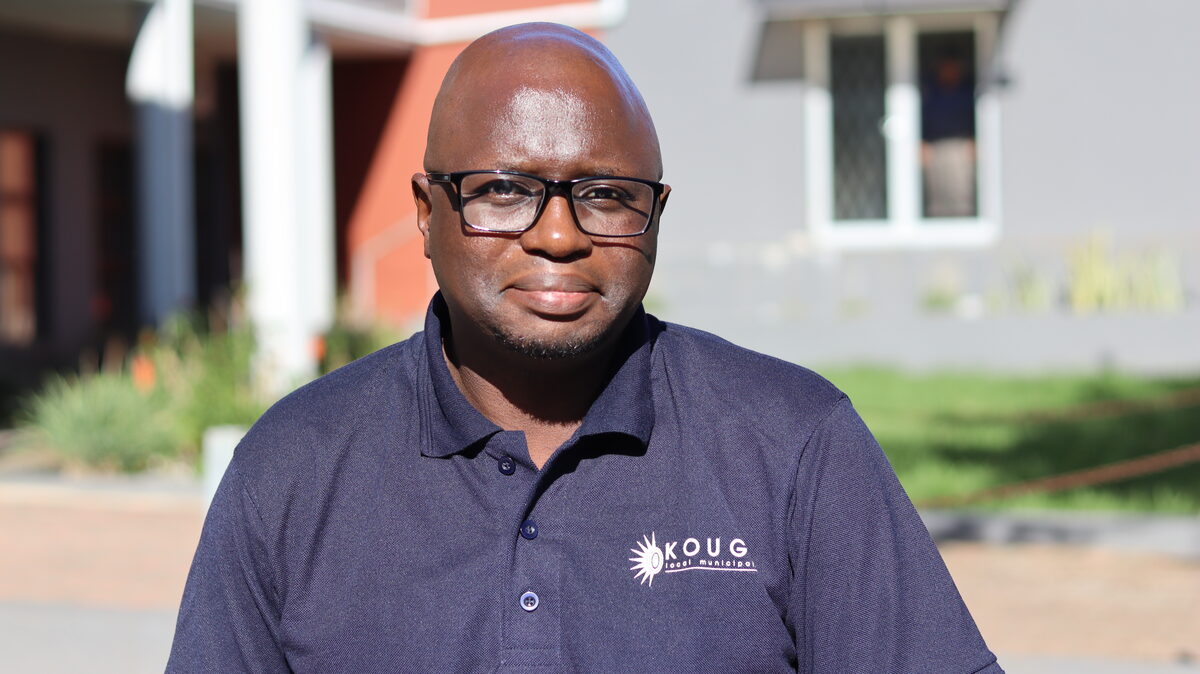 Ndumiso Nongcaula standing in front of a building with Kouga Local Municipality branded clothing.