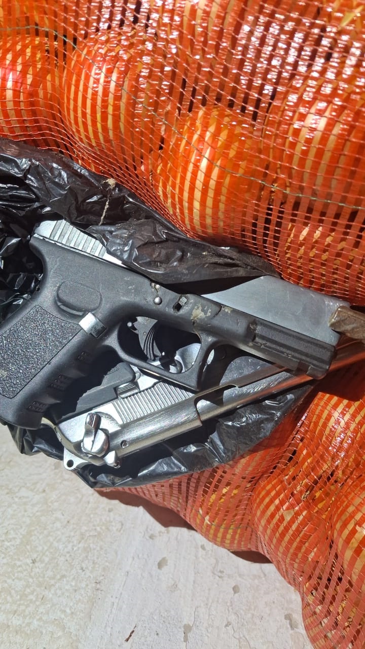 A firearm laid on a bag of onions.