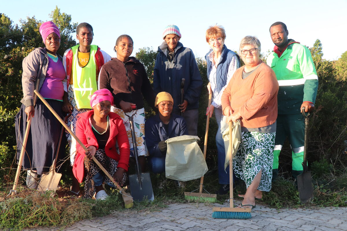A group of workers standing alongside each other with cleaning supplies.