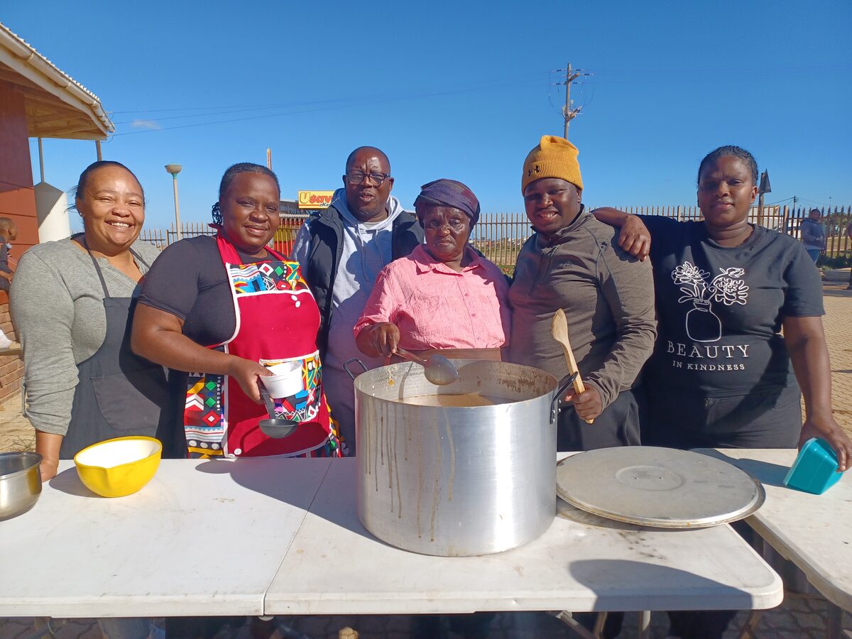 A group of people standing behind a pot filled with soap.