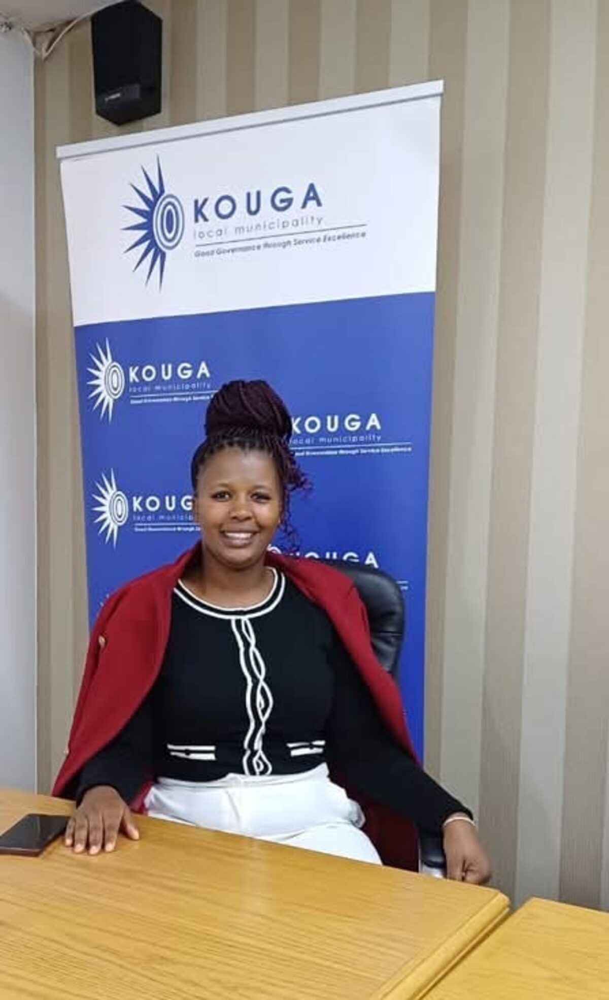 Ziyanda Kilimani standing in front of a Kouga Municipality banner.