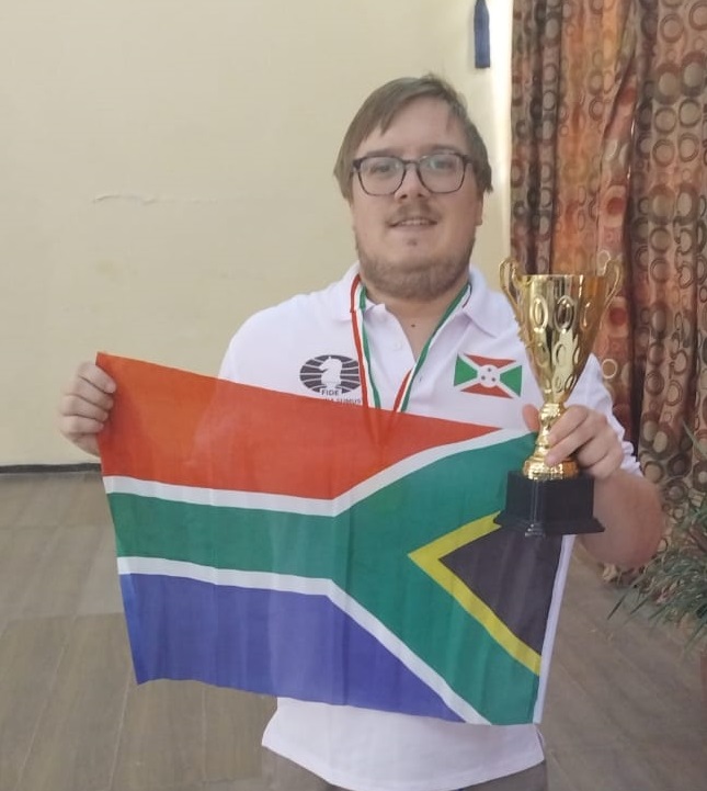 Justin Rishworth holding his trophy and a South African flag.