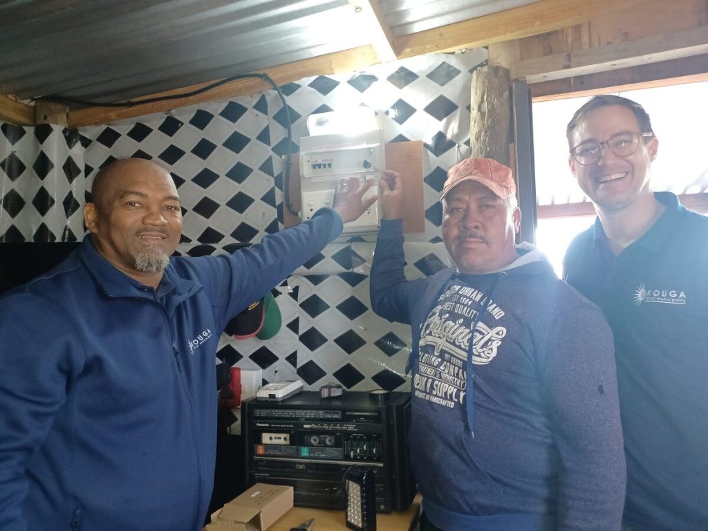 Jaques Alexander, Carel Smit and Kouga Executive Mayor Hattingh Bornman standing alongside each other as they turn on a light behind them.  