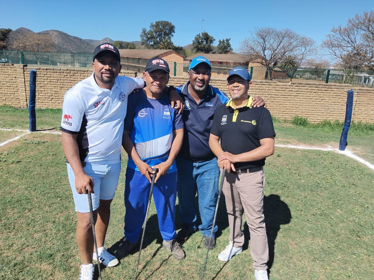 Four people standing alongside each other with golfing gear.